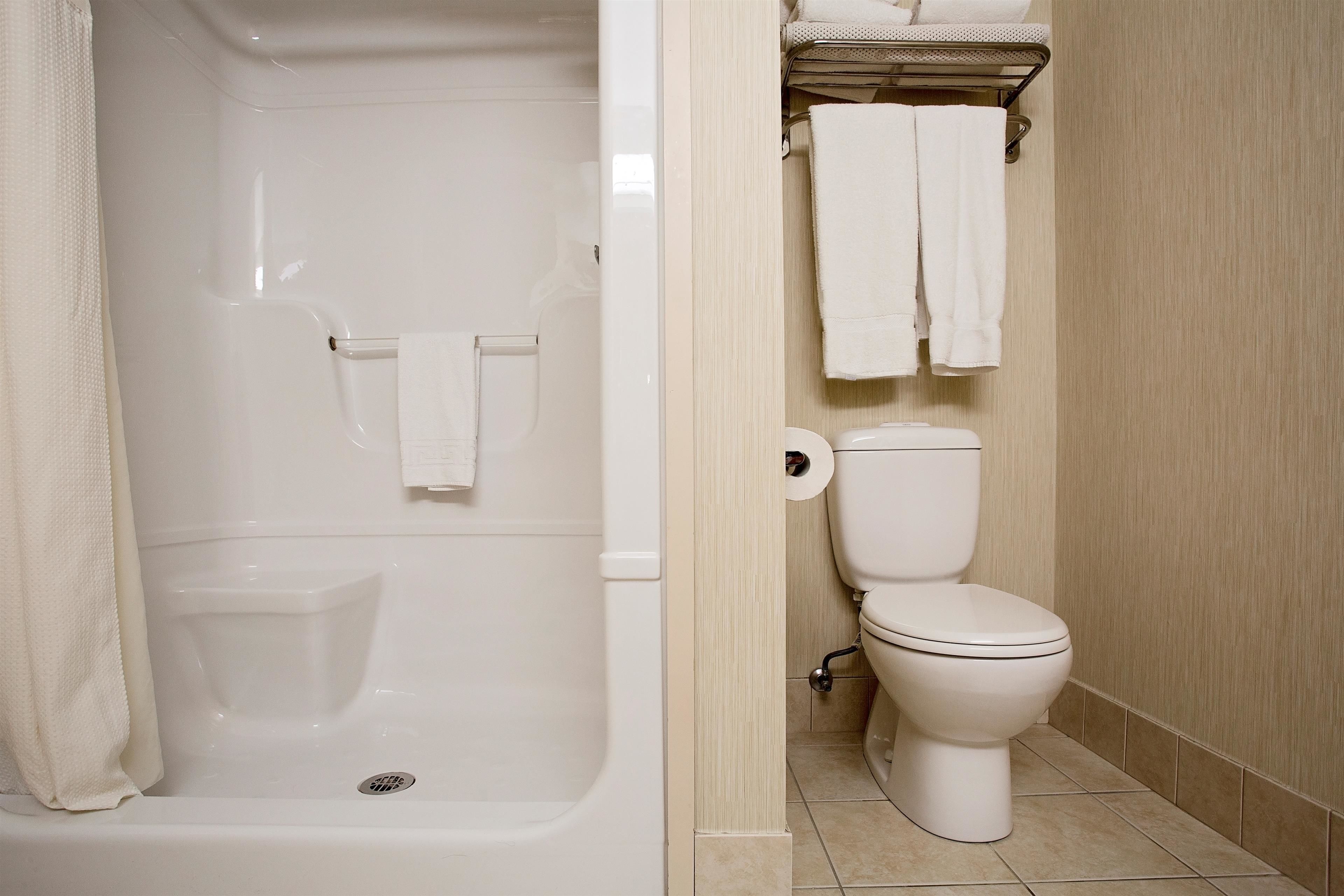 A bathroom with a bathtub, toilet, and a shelf with towels.