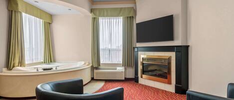 Habitación de hotel con una bañera grande, chimenea, televisor de pantalla plana y alfombra roja con estampado.