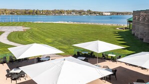 Een terras buiten met witte parasols en tafels, met uitzicht op een meer.