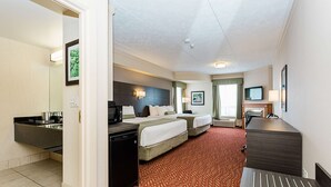 Een hotelkamer met een kitchenette, twee bedden, een bureau en een televisie.
