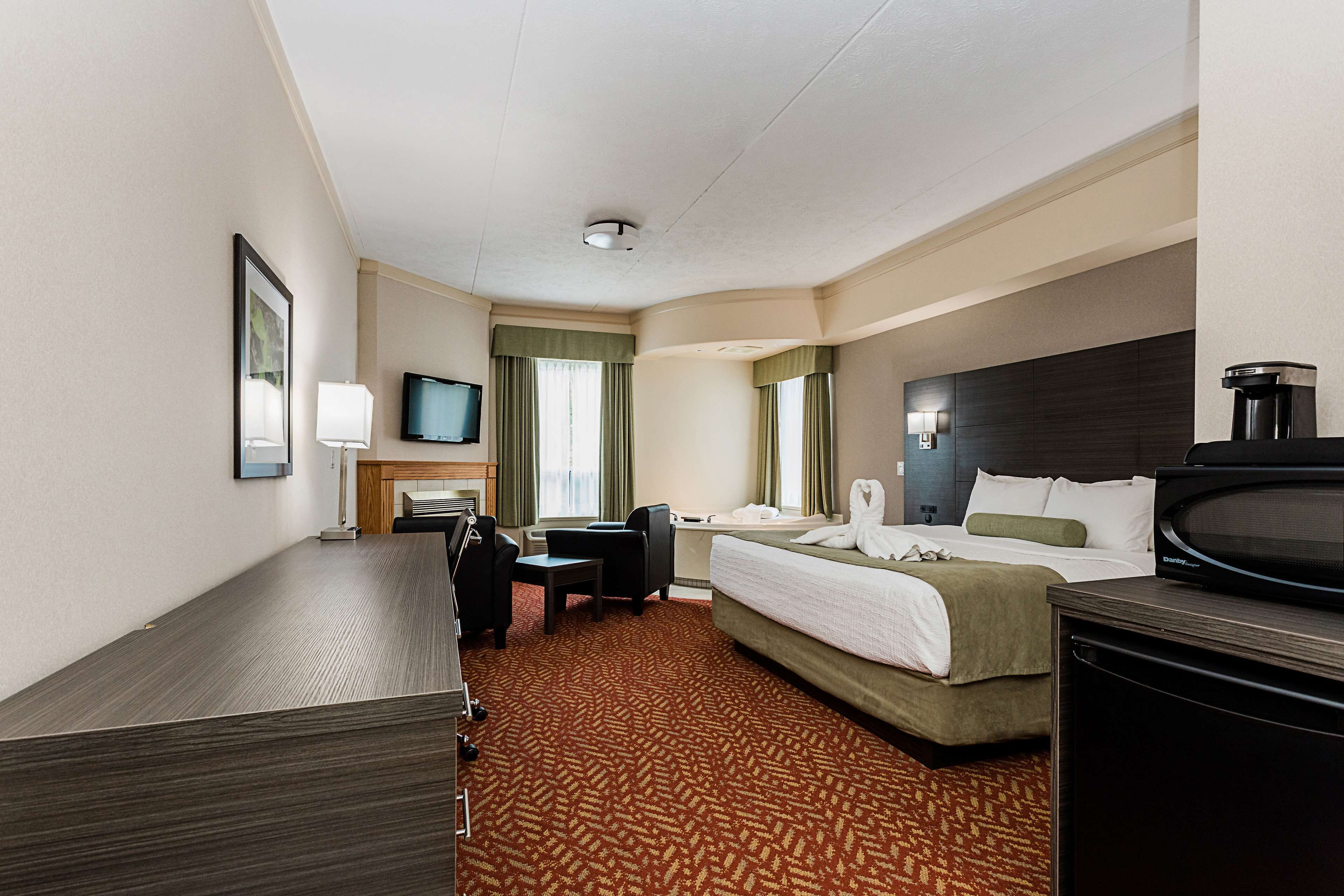 Habitación de hotel con cama, escritorio, silla, televisor y cafetera.