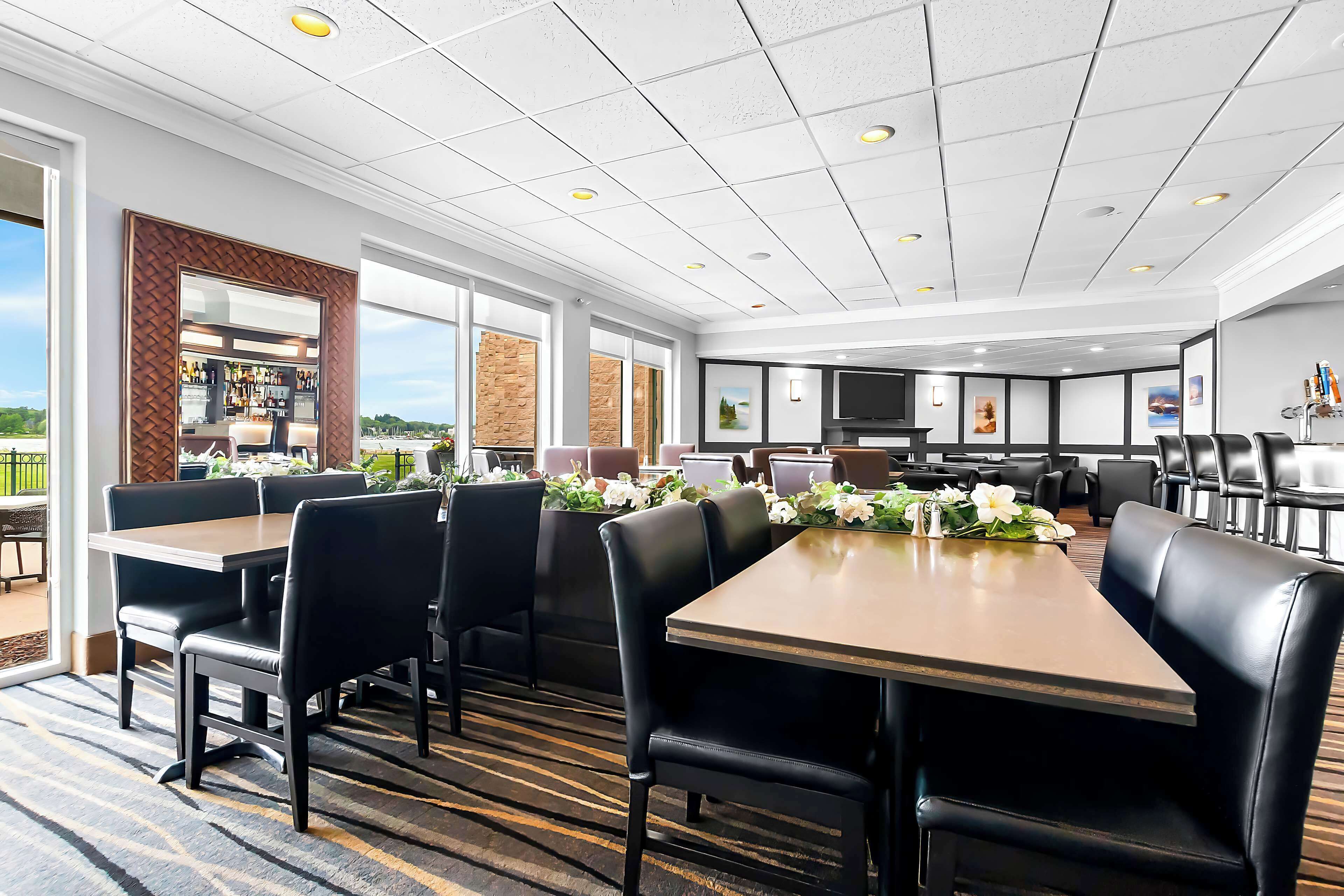 A conference room with tables and chairs, a kitchen area, and a view of the outdoors.