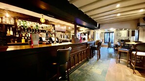 A bar area with a counter, stools, and a variety of bottles. There are tables and chairs in the background. - The Great Barr Hotel (Birmingham)