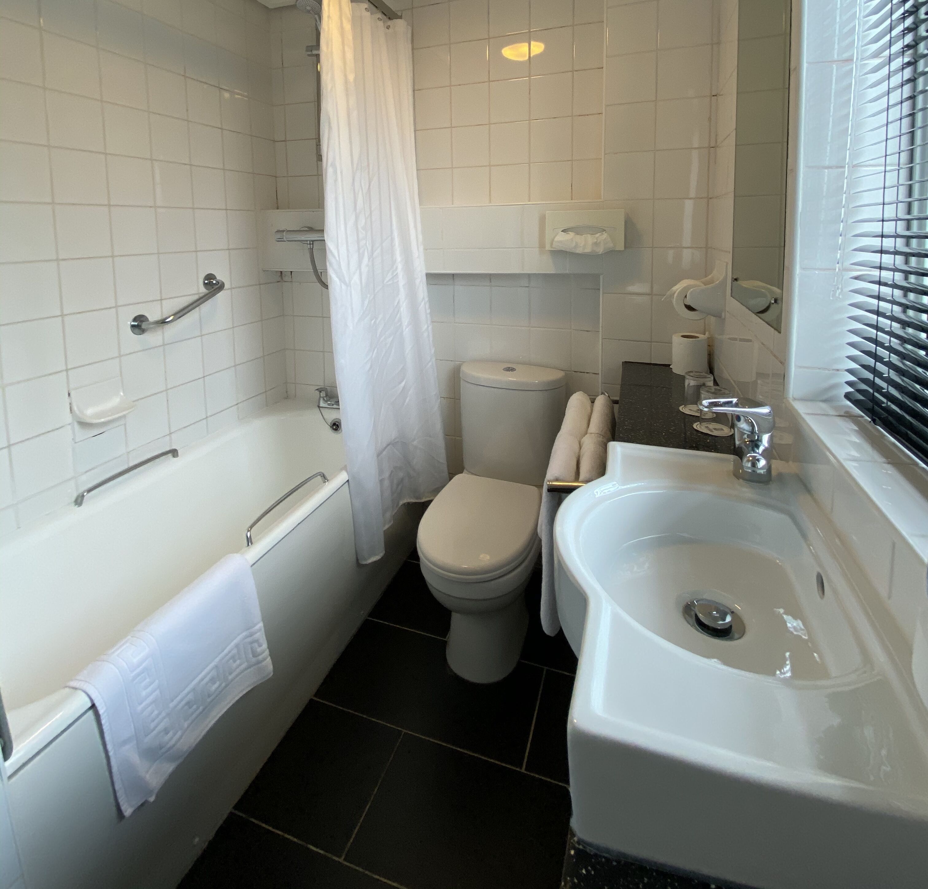 A bathroom with a bathtub, toilet, sink, and a shower curtain.