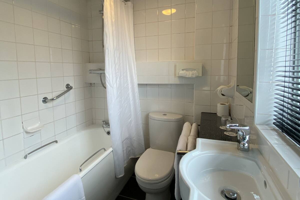 A bathroom with a bathtub, toilet, sink, and a shower curtain.