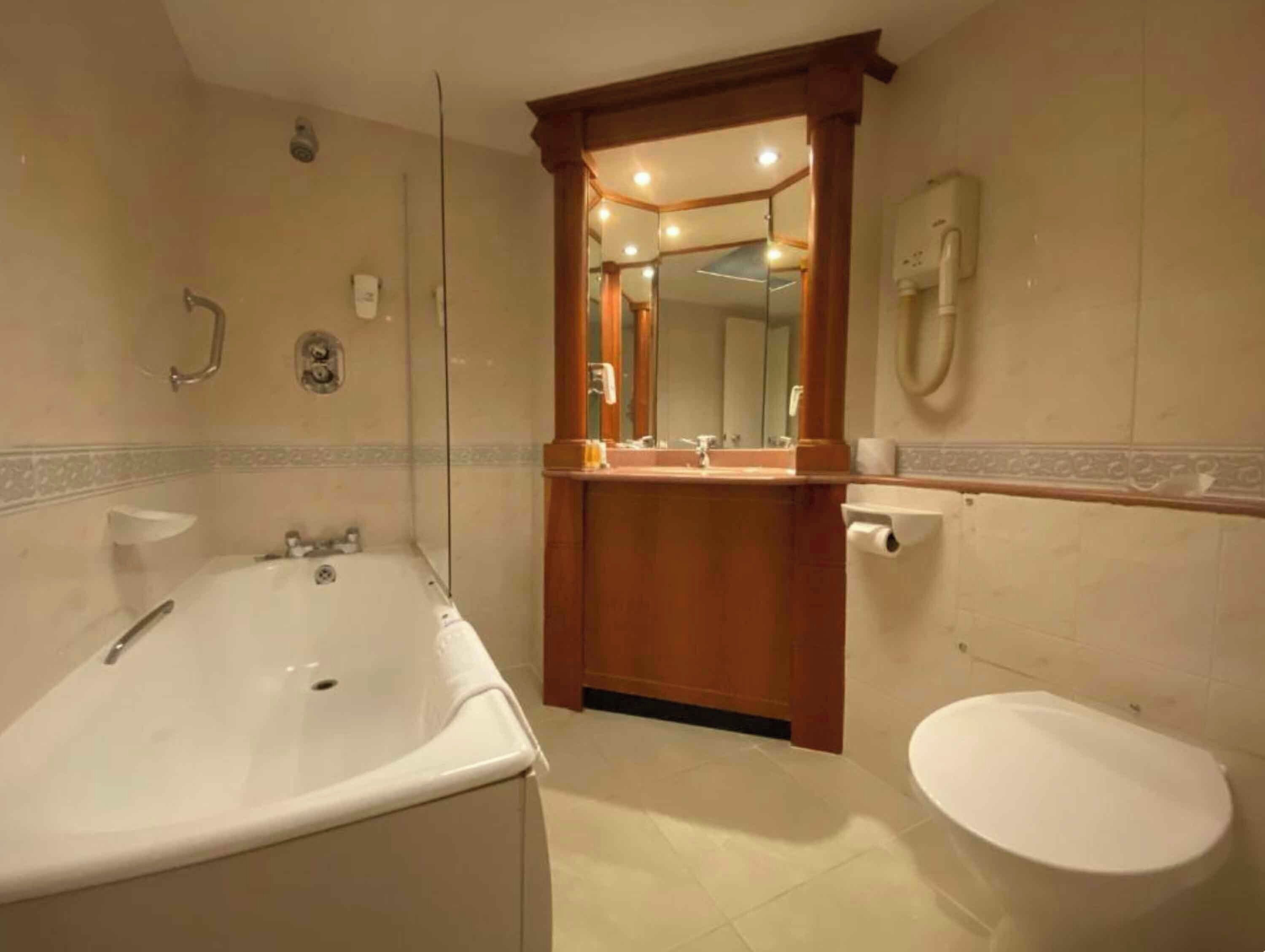 A bathroom with a bathtub, toilet, and a mirror above the sink.
