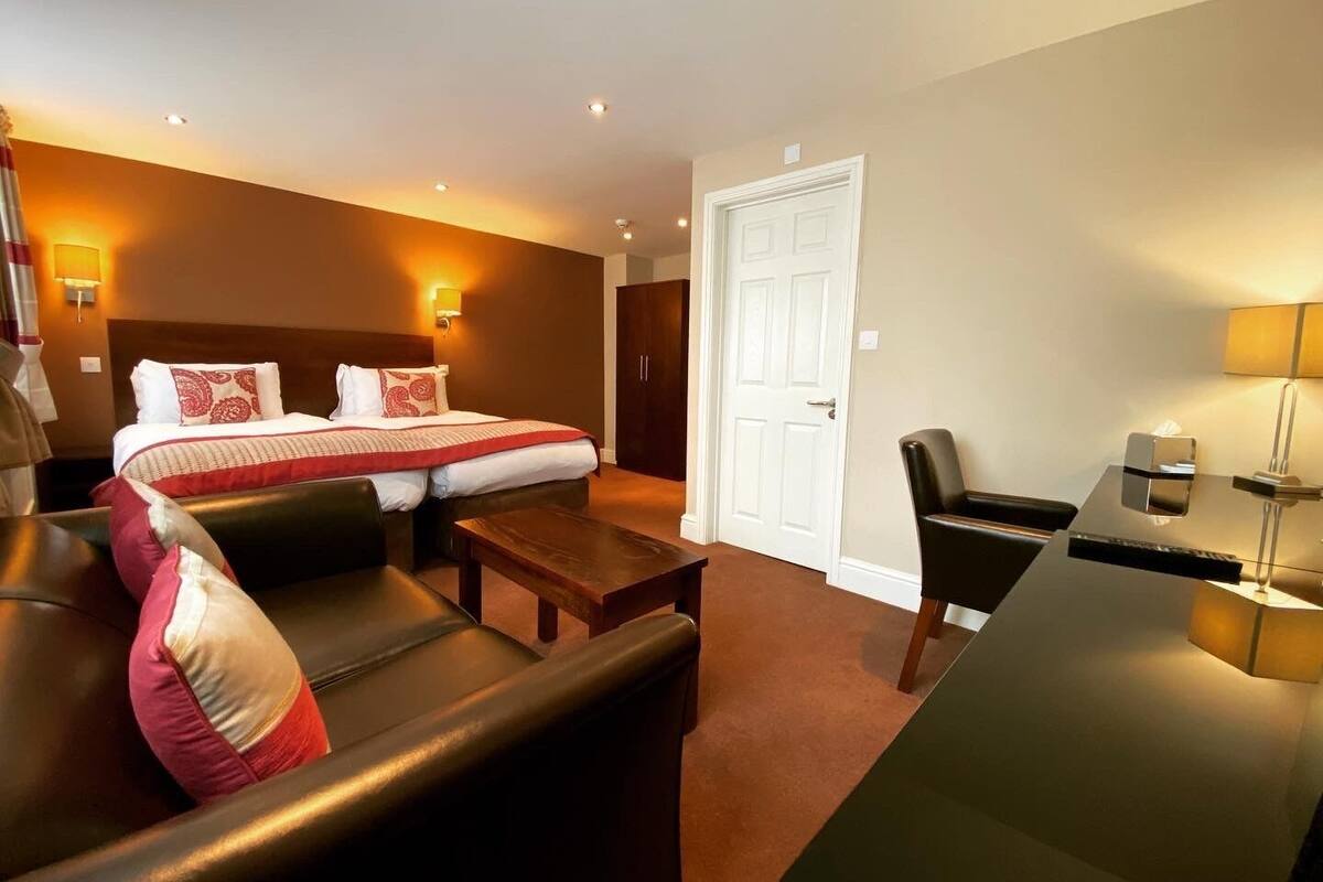A hotel room with a bed, a sofa, a desk, and a chair.