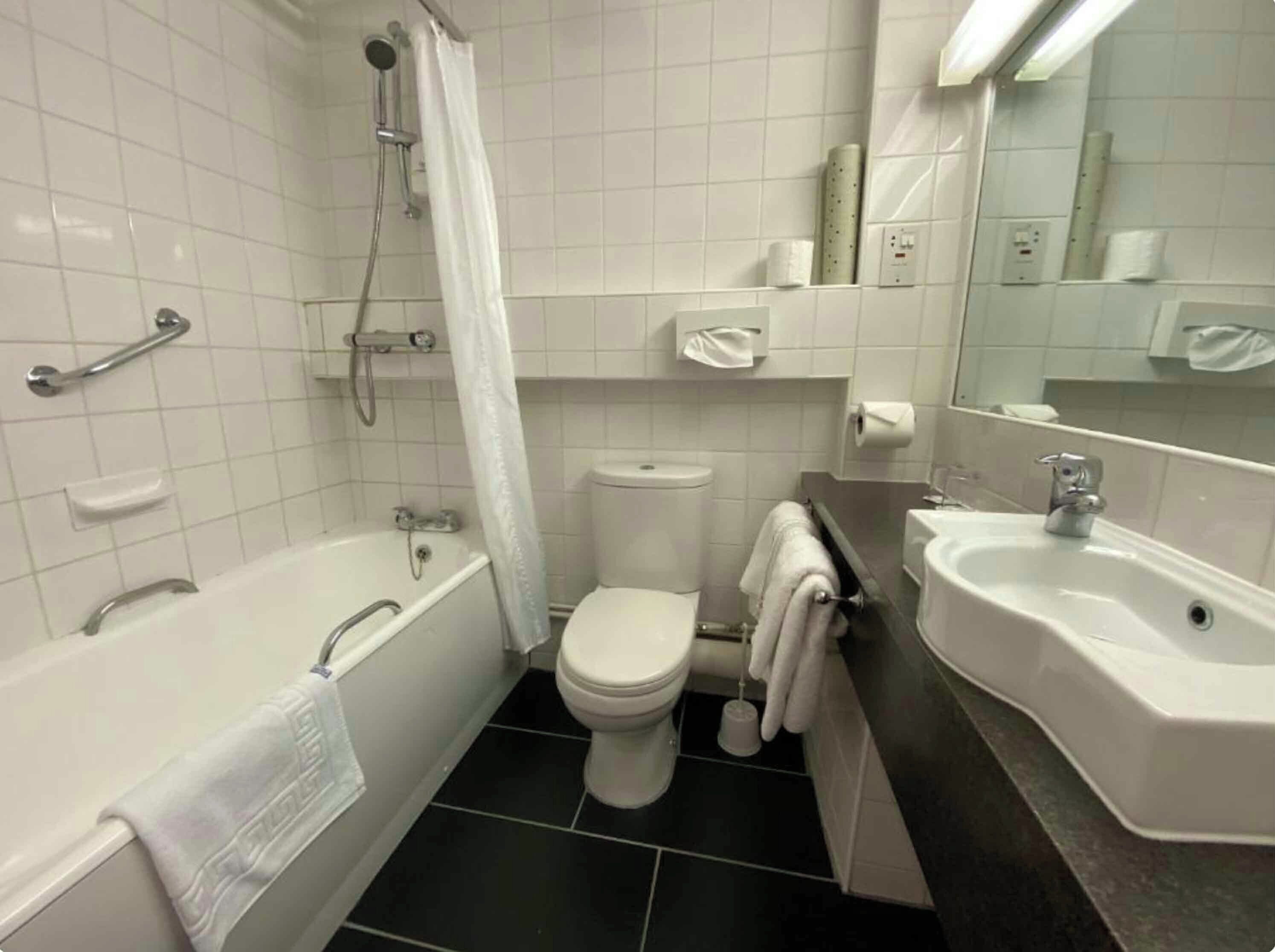 A bathroom with a bathtub, toilet, and two sinks.