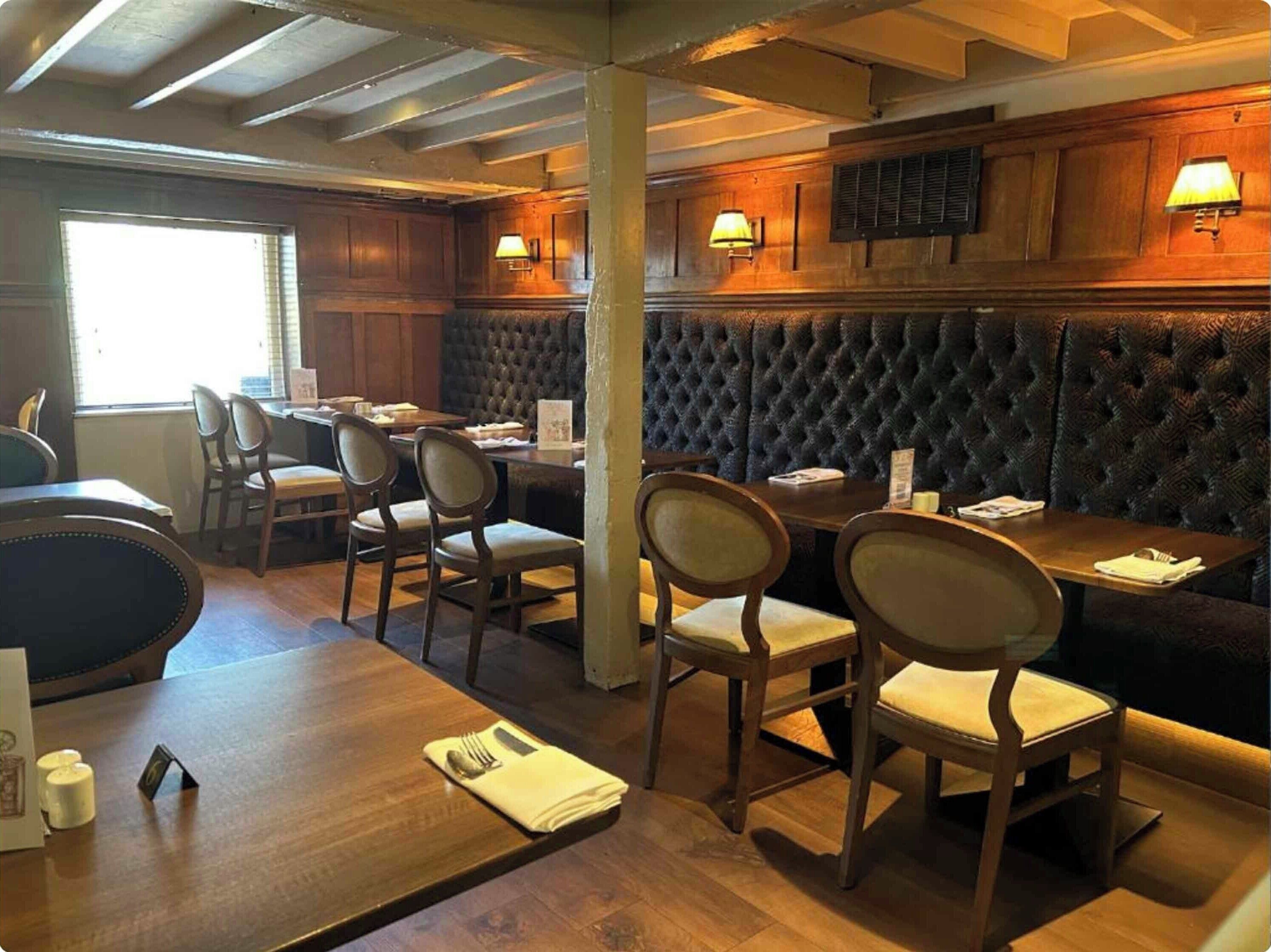 A restaurant interior with wooden tables, cushioned booths, and wall-mounted lamps.