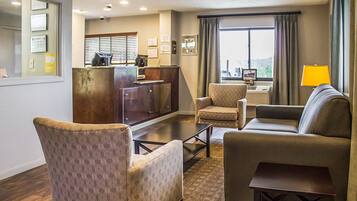 A hotel lobby with a reception desk, seating area, and large windows.
