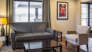 A living room with a sofa, armchair, coffee table, and a lamp.