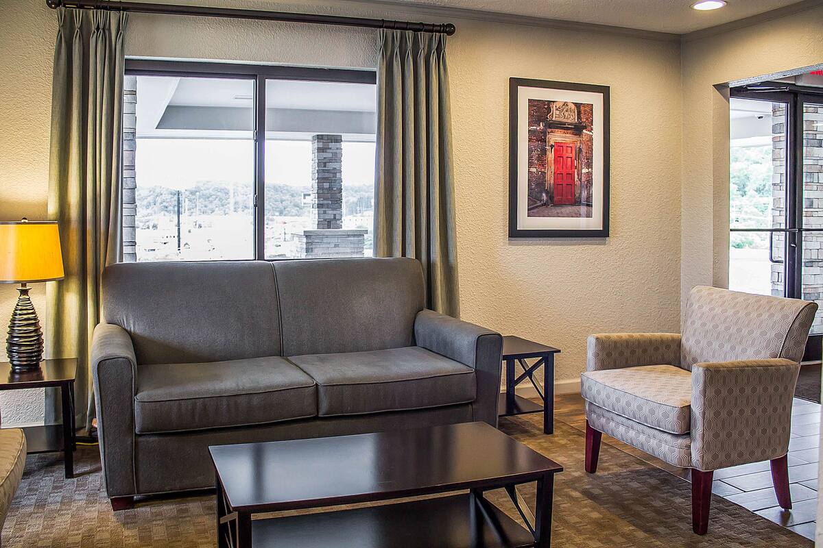 A living room with a sofa, armchair, coffee table, and a lamp.