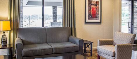A living room with a sofa, armchair, coffee table, and a lamp.