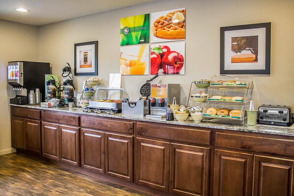Una barra de desayuno con diversos alimentos, una máquina de café y un tostador.