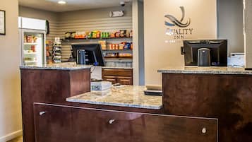 A hotel reception area with a marble counter, a coffee machine, and shelves stocked with snacks and beverages.