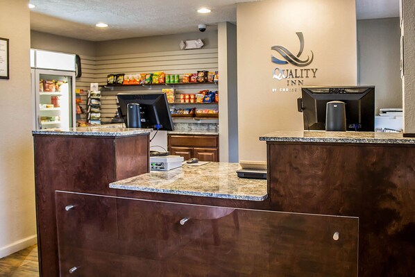 A hotel reception area with a marble counter, a coffee machine, and shelves stocked with snacks and beverages.