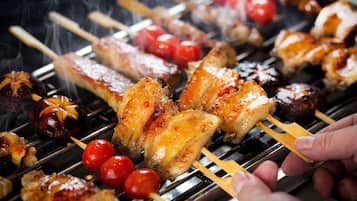 A close-up of various grilled meats and vegetables on a grill.