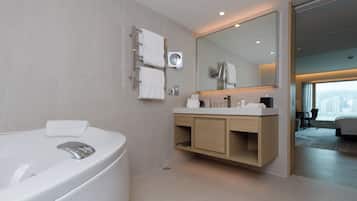 A modern bathroom with a large bathtub, a vanity with a mirror, and a view of a cityscape through a window.