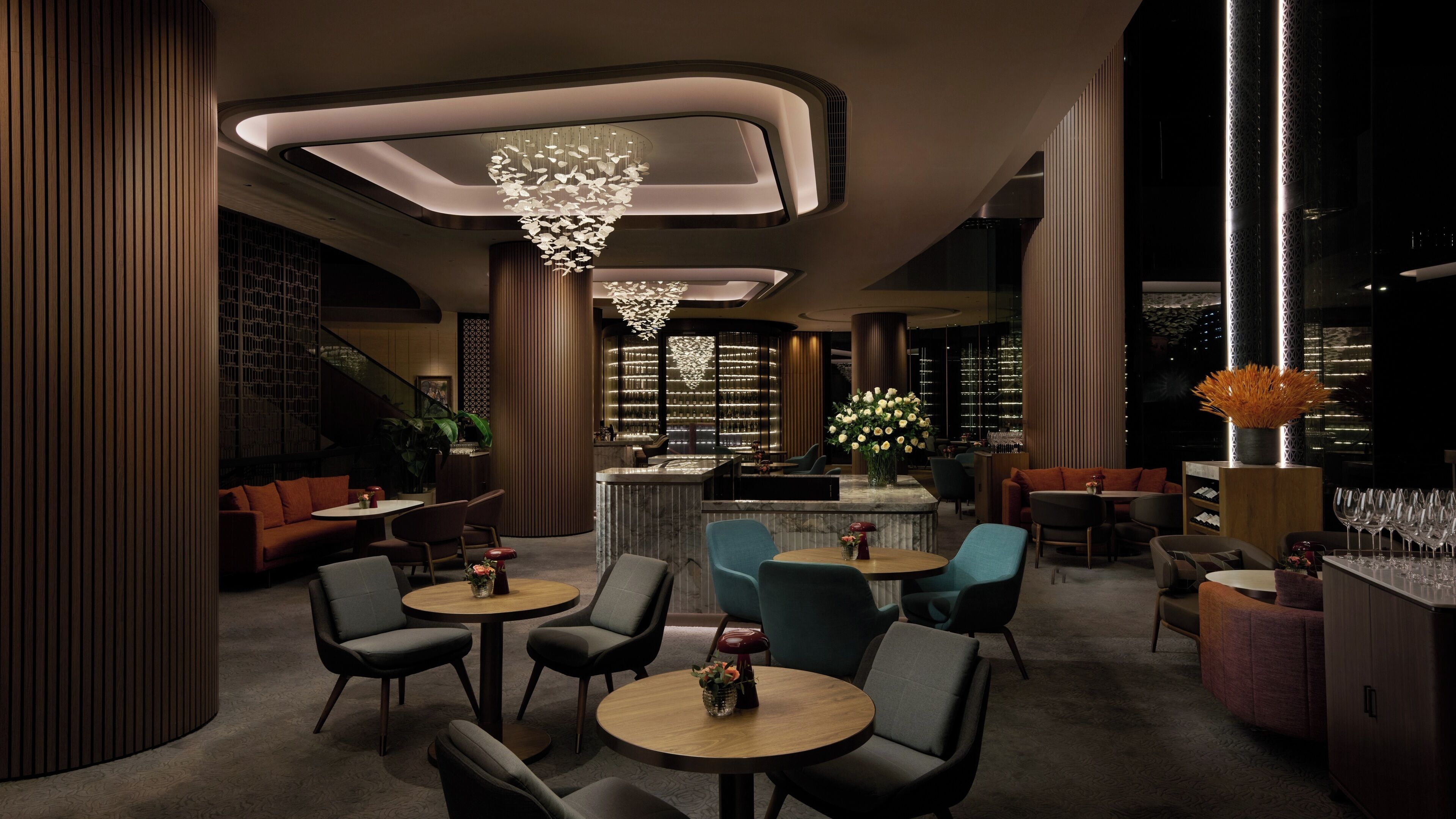A modern interior with round tables and chairs, a bar area, and a decorative ceiling light.