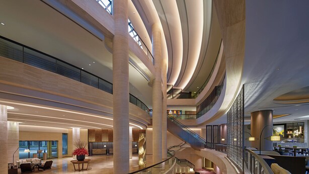 A modern hotel lobby with a spacious layout, multiple levels, and a central staircase. - New World Millennium Hong Kong Hotel (Kowloon)