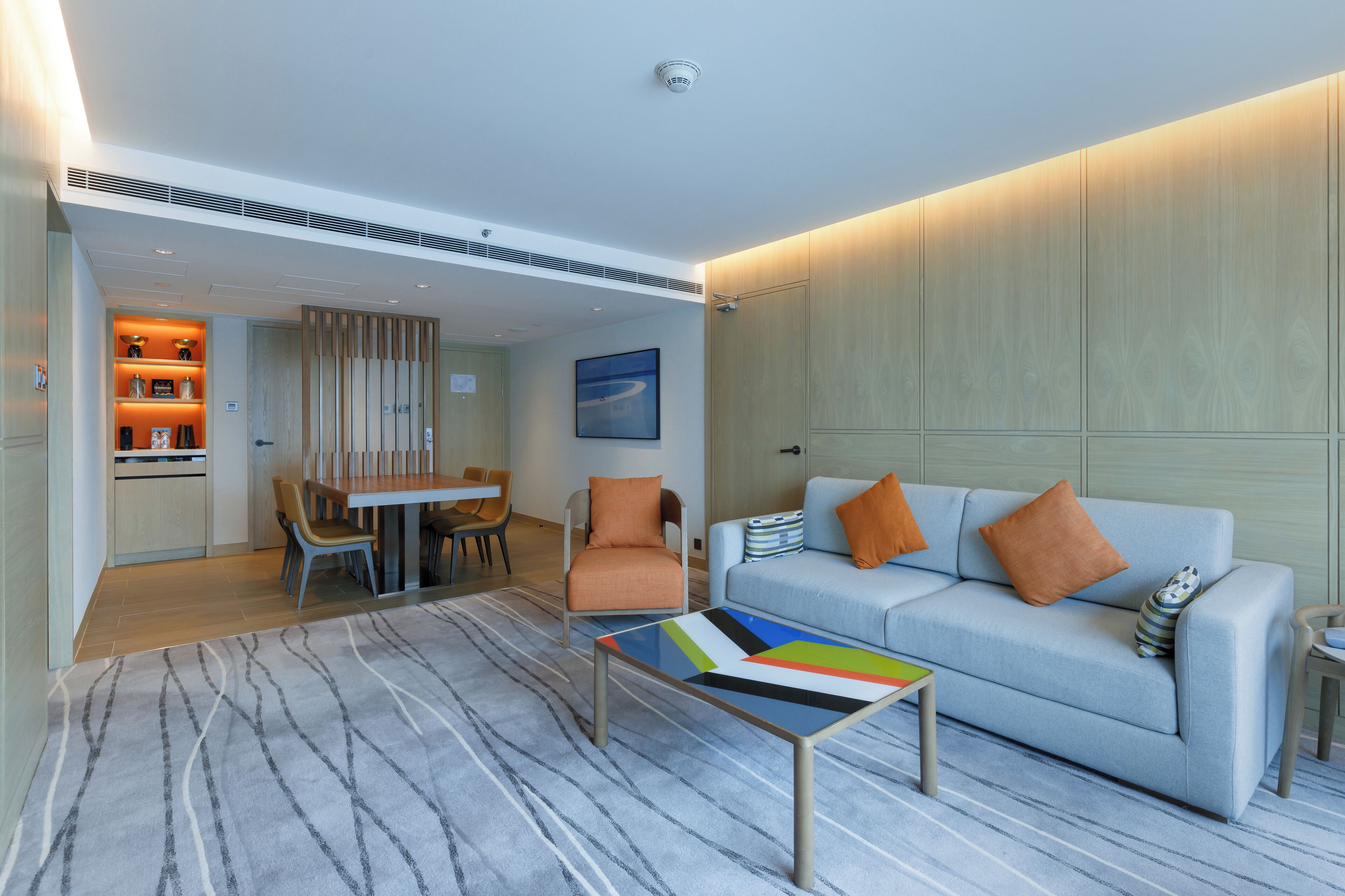 A modern living room with a sofa, armchairs, a coffee table, and a dining area with chairs and a table.