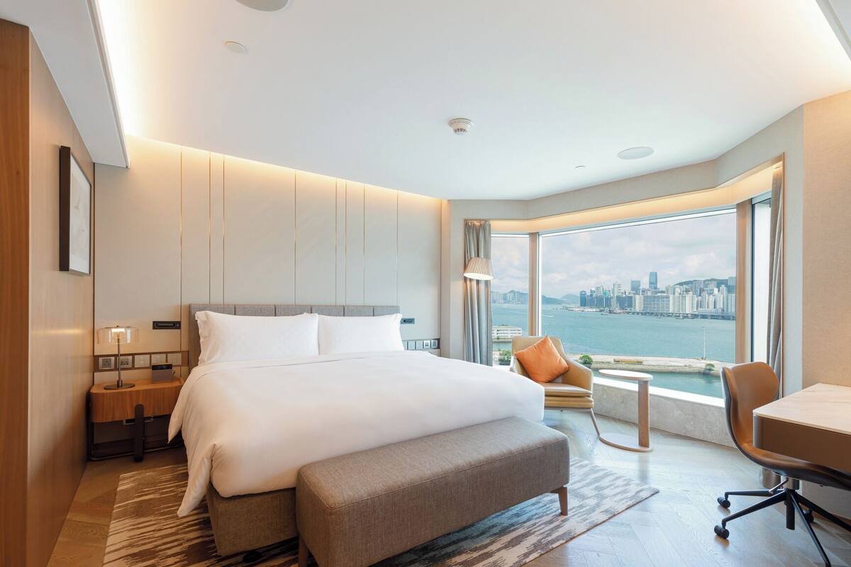 Une chambre d’hôtel moderne avec un grand lit, un bureau et une vue sur le paysage urbain.