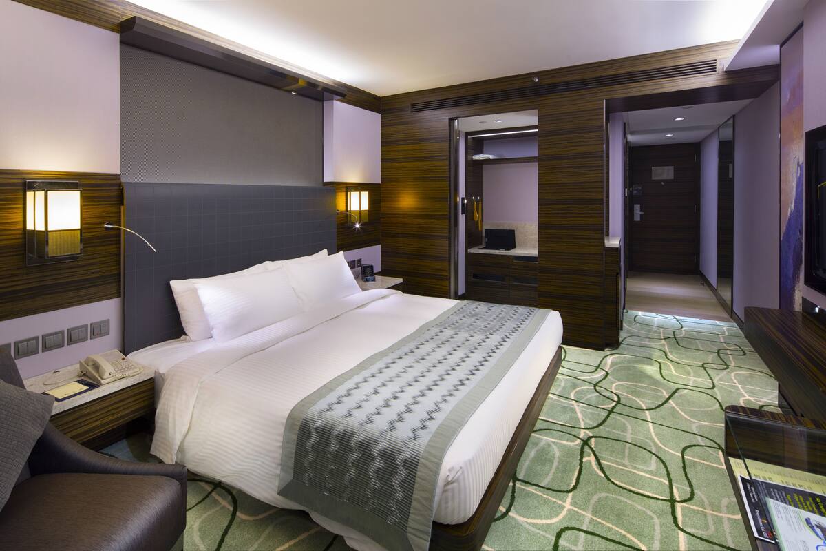 Une chambre d’hôtel équipée d’un lit, d’une table de chevet, d’une lampe et d’un téléviseur.