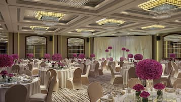 A banquet hall with round tables, white tablecloths, and pink floral centerpieces.