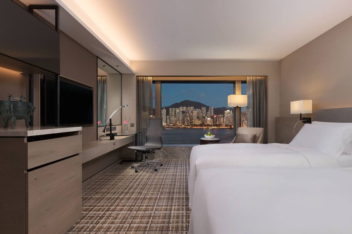 Une chambre d’hôtel équipée d’un lit, d’un bureau, d’une chaise et offrant une vue sur le paysage urbain.