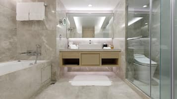 A modern bathroom with a bathtub, a glass-enclosed shower, a vanity with a sink, and a toilet.
