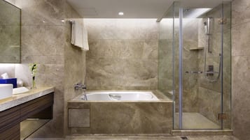 A modern bathroom with a glass-enclosed shower, a freestanding bathtub, and a vanity with a mirror and towel rack.