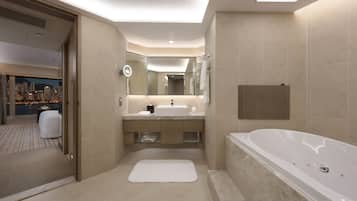 A modern bathroom with a large bathtub, a vanity with a mirror, and a view of a cityscape through an open door.