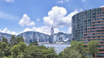 Paisagem urbana com edifícios modernos, um arranha-céu imponente e um corpo de água em primeiro plano.