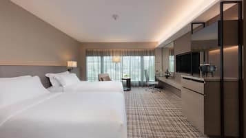 Een hotelkamer met twee bedden, een bureau, een stoel, een televisie en een grote spiegel.