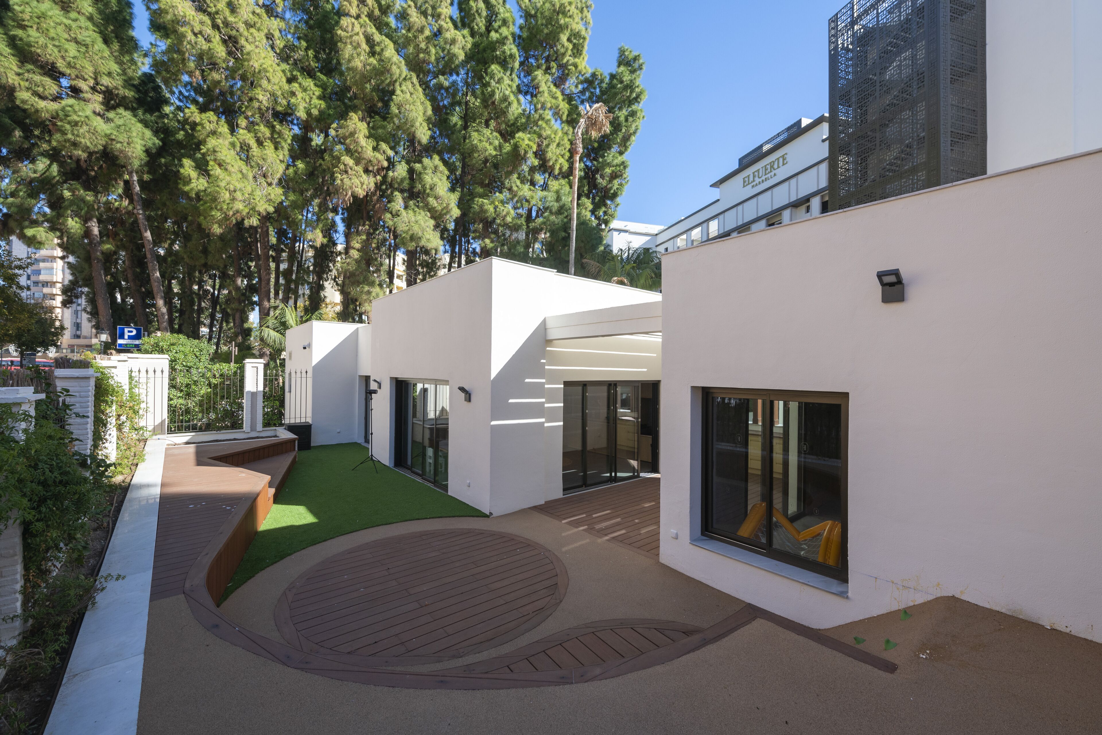 Un edificio moderno con patio interior, ventanas amplias y fachada blanca.