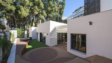 Un edificio moderno con patio interior, ventanas amplias y fachada blanca.