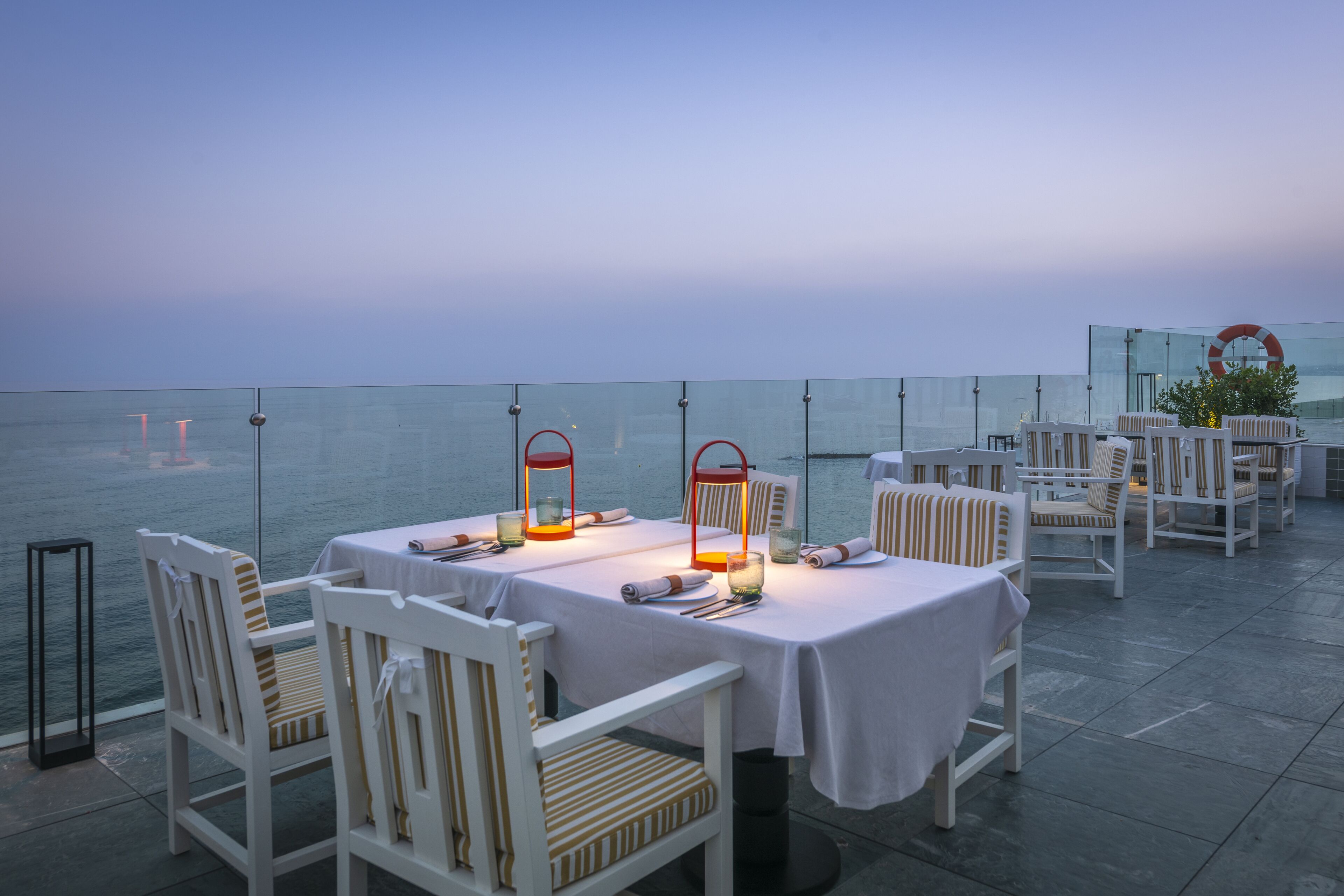 A dining area with tables and chairs, overlooking a body of water.