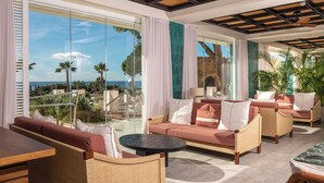 Suíte de hotel moderna com uma varanda ampla, assentos confortáveis e vista para o oceano.