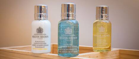 Three bottles of Molton Brown toiletries in a wooden tray.
