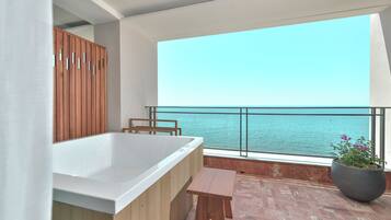 Un balcón con vista al mar, un armario de madera, una bañera y una planta en maceta.