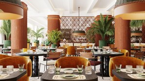 Um restaurante com mesas redondas, cadeiras e plantas em vasos.