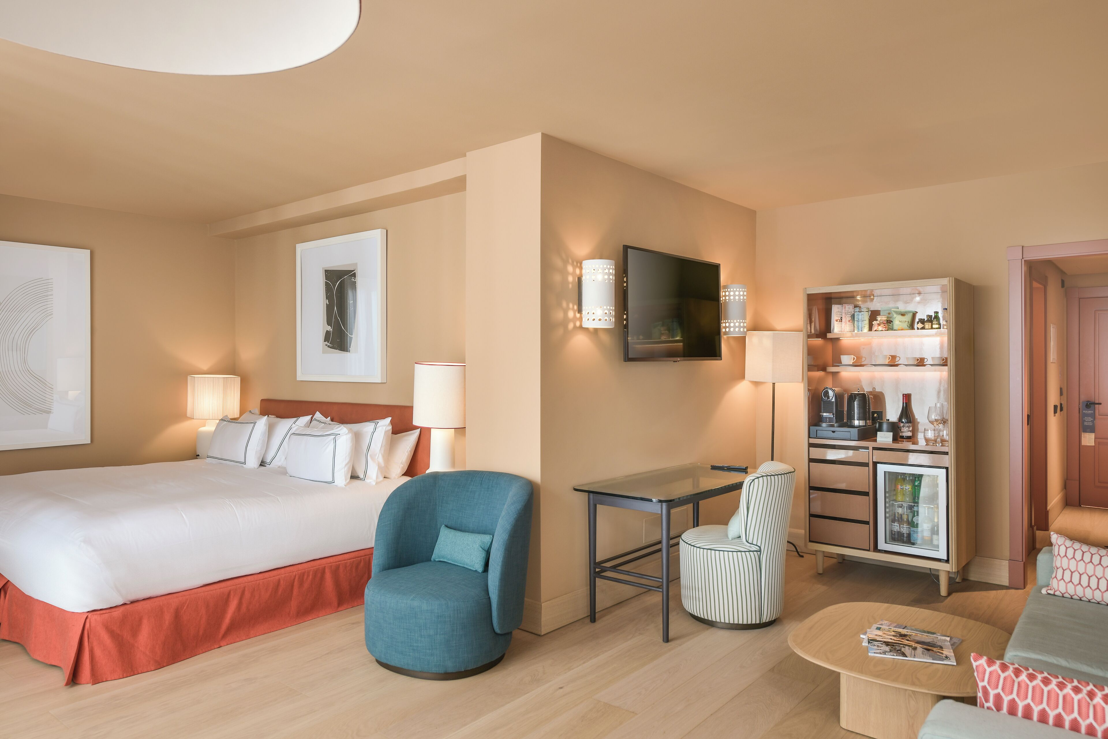 Habitació d'hotel amb un llit, escriptori, cadira, televisió i un minibar.