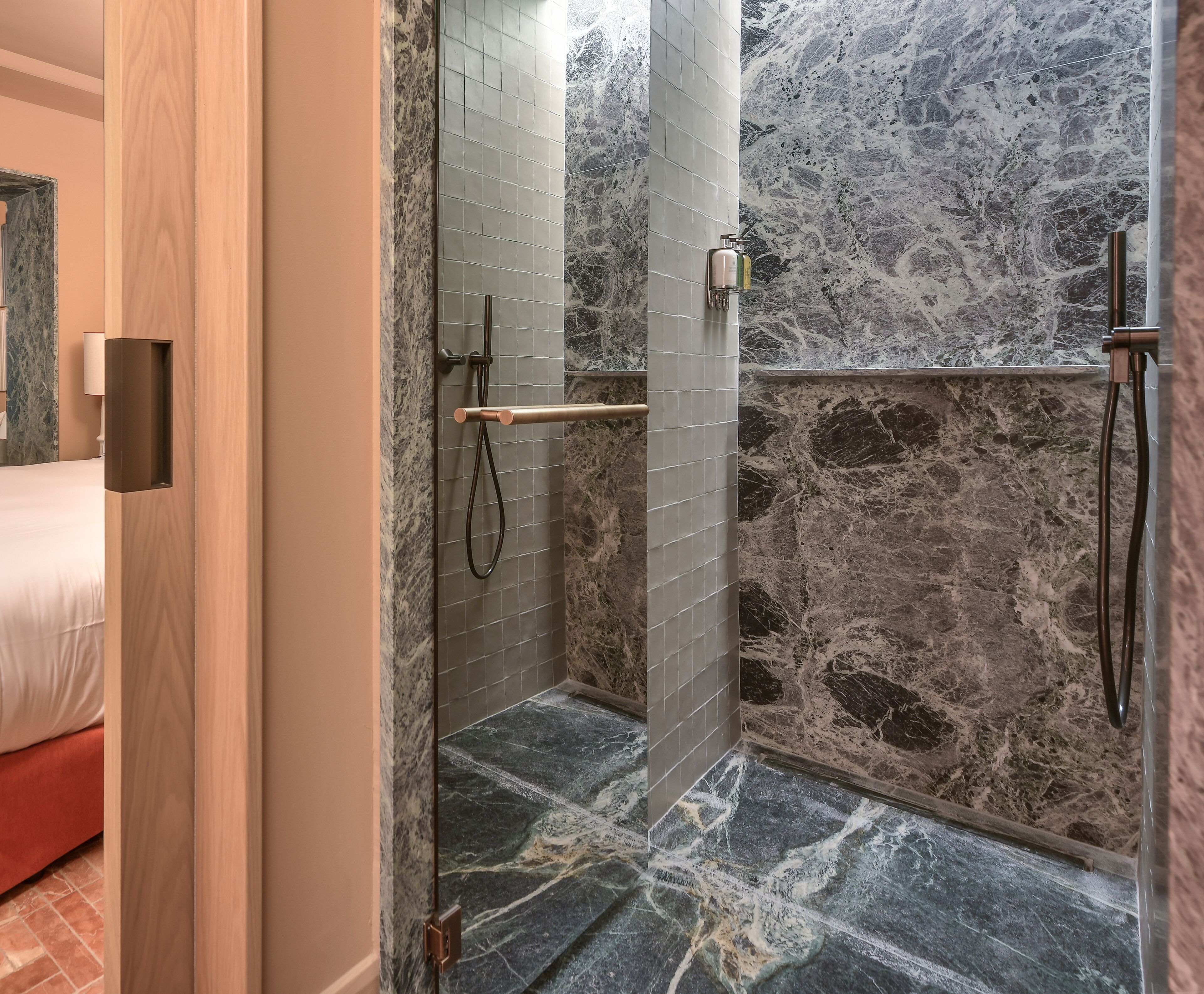 Een douche met een marmeren wand en een houten deur.
