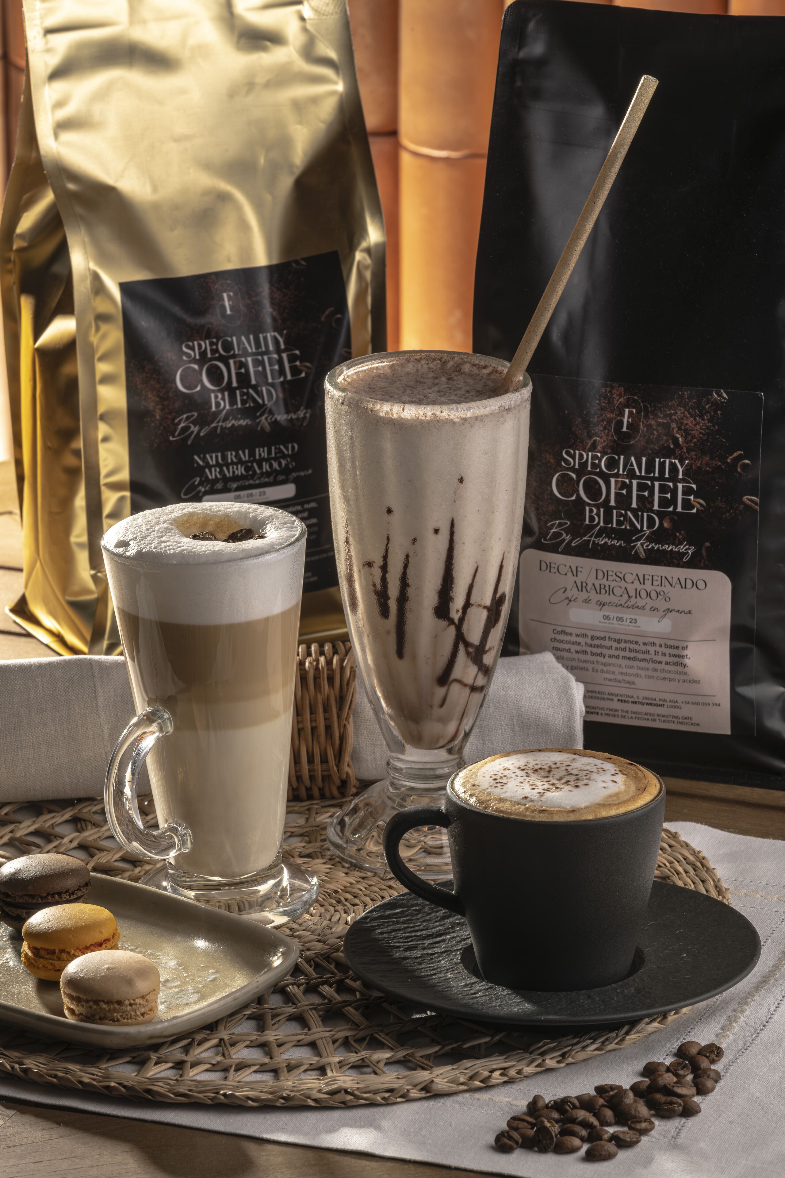 A coffee setting with a tall glass of coffee, a cup, and a bag of coffee blend.