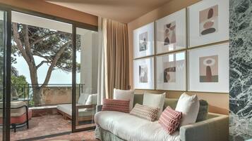A modern living room with a sofa, a coffee table, and a balcony with a view of trees.