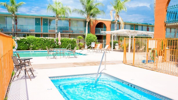A hotel with a swimming pool, lounge chairs, and palm trees. - GLH Hotel (Tucson)