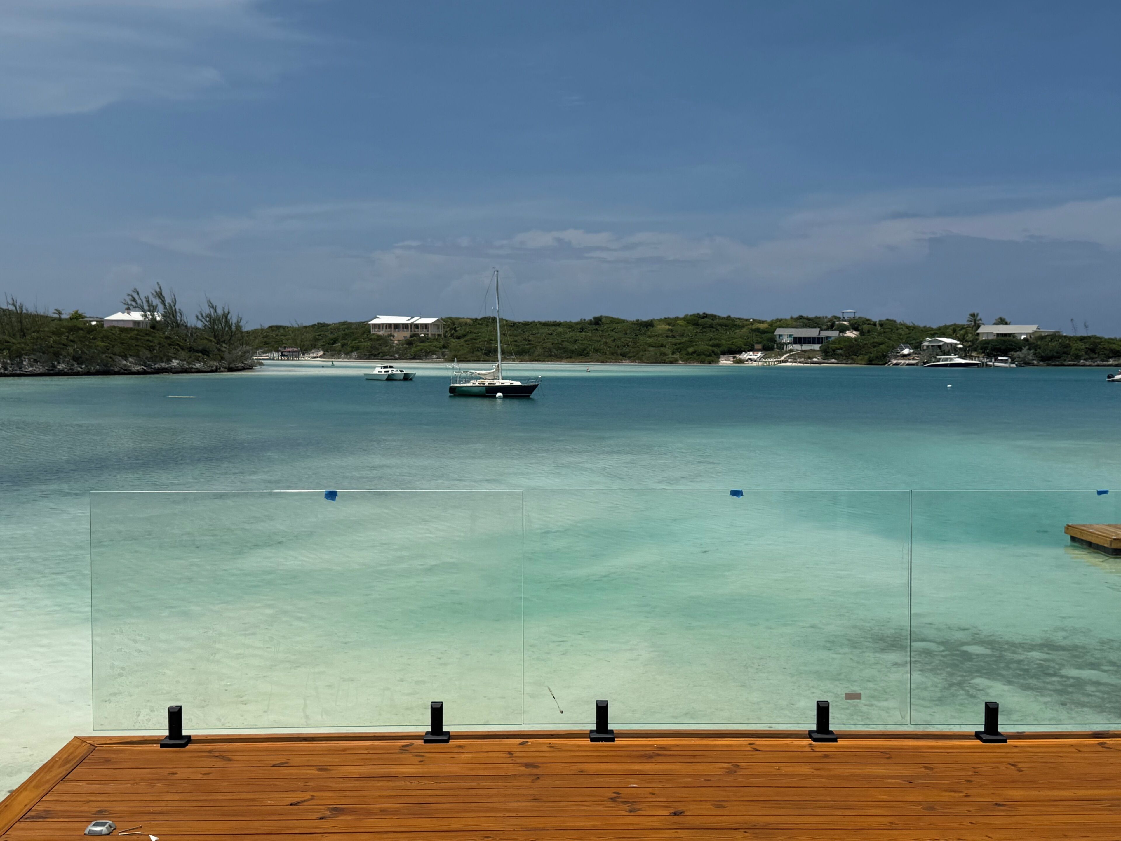 A wooden deck with a clear view of turquoise waters, boats, and distant buildings.
