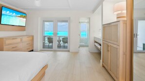 Habitación de hotel moderna con cama, televisión, balcón con vistas al mar y armario de madera.