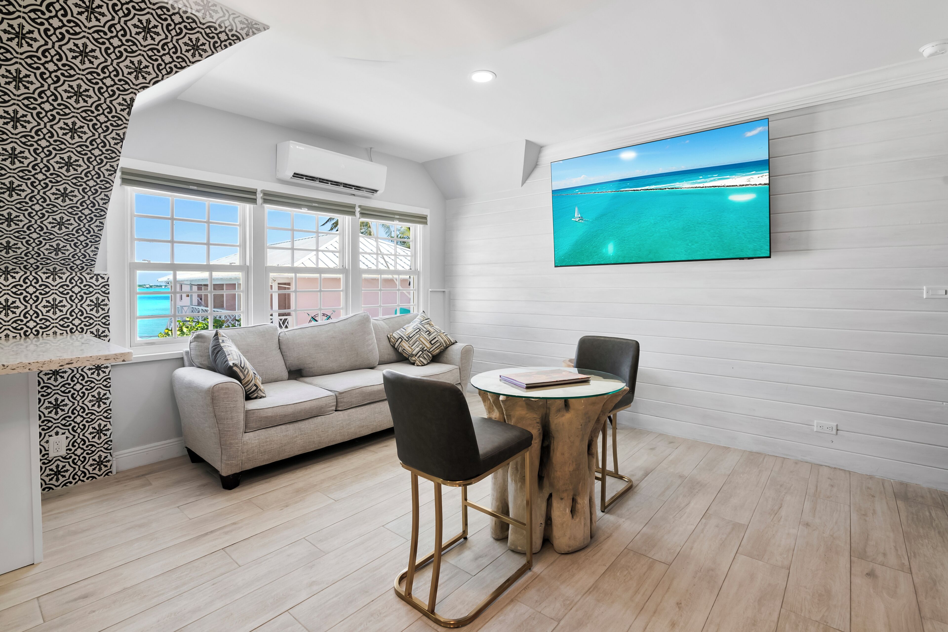 A modern living room with a large TV, a sofa, two chairs, and a wooden coffee table.