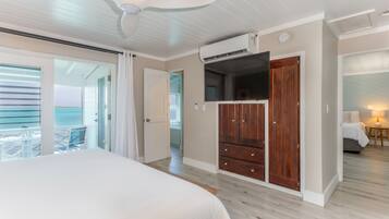 Ein Schlafzimmer mit einem Bett, einem Deckenventilator, einer Klimaanlage, einem Holzschrank und Blick auf den Balkon.